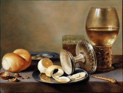 Monochrome Banketje with two pewter dishes, an overturned silver tazza, a gilt knife, a glass with beer, a rummer with wine, a roll of bread, nuts, olivers and a half peeled lemon