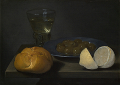 Stilleven van brood, bord met olijven, roemer en citroen