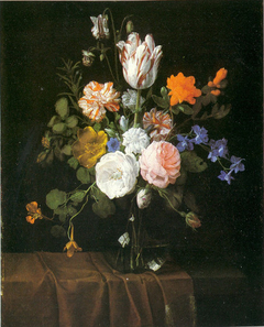Flowers in a glass vase on a partly draped stone ledge