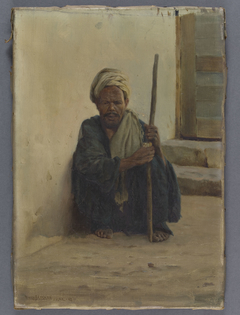 Louxor, arabe tenant un bâton assis dans une rue