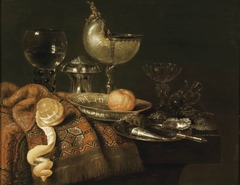 Still life with nautilus cup, salt cellar, roemer, façon de Venise glass and table carpet by Willem Claesz Heda
