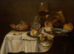 Still life with crab, bread, lemon, roemer, perfume bottle and pewter plates by Willem Claesz Heda