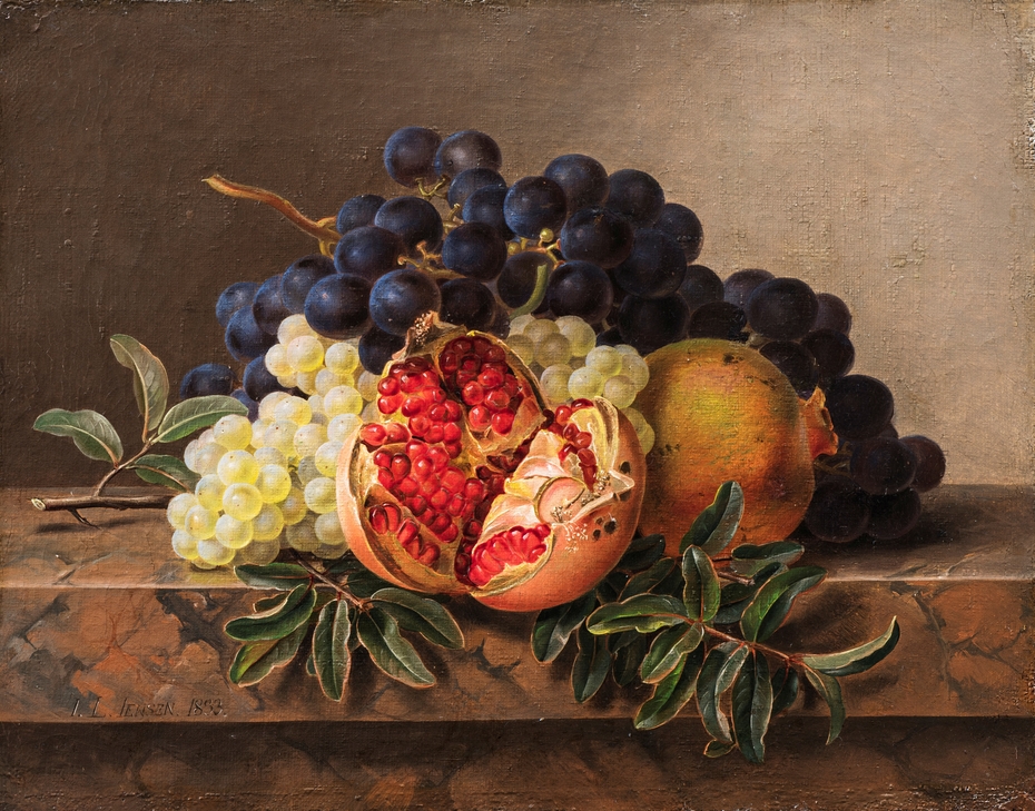 Pomegranates and green and blue grapes on a marble frame